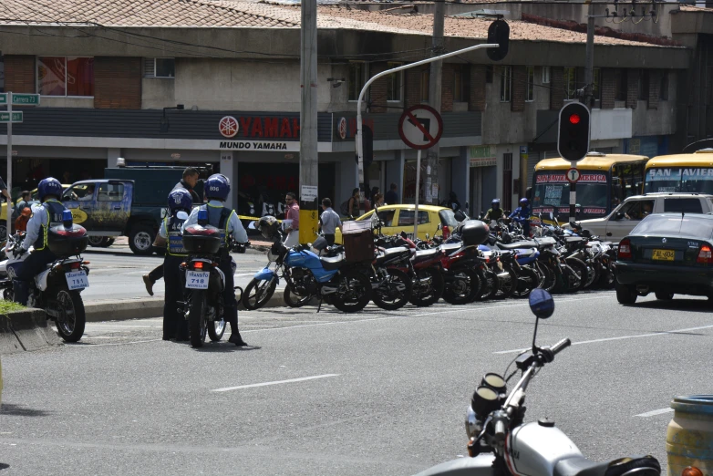 several people on motor bikes and vehicles are parked at an intersection