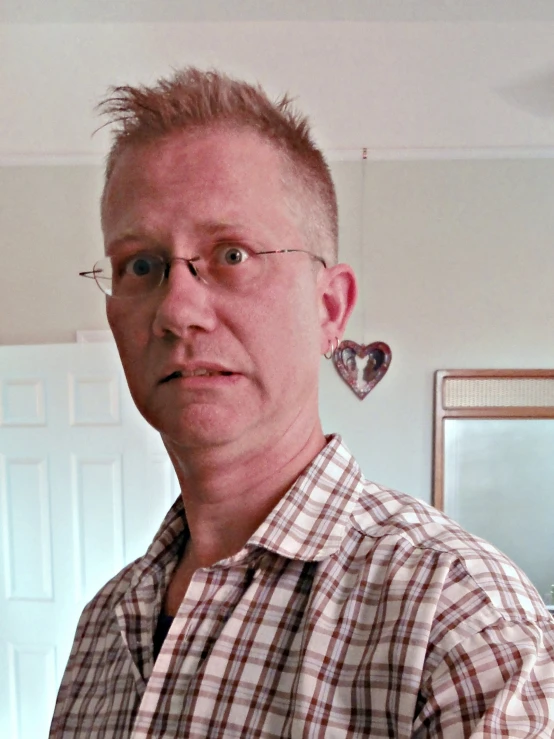 man with red glasses wearing checked shirt in living room