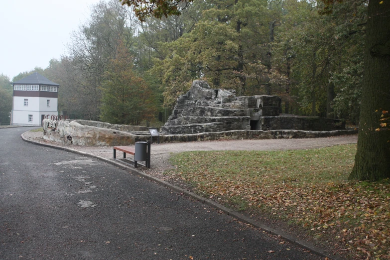 a park with a stone structure and a stone bench near a tree
