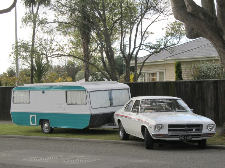 two cars and a camper on a small suburban street