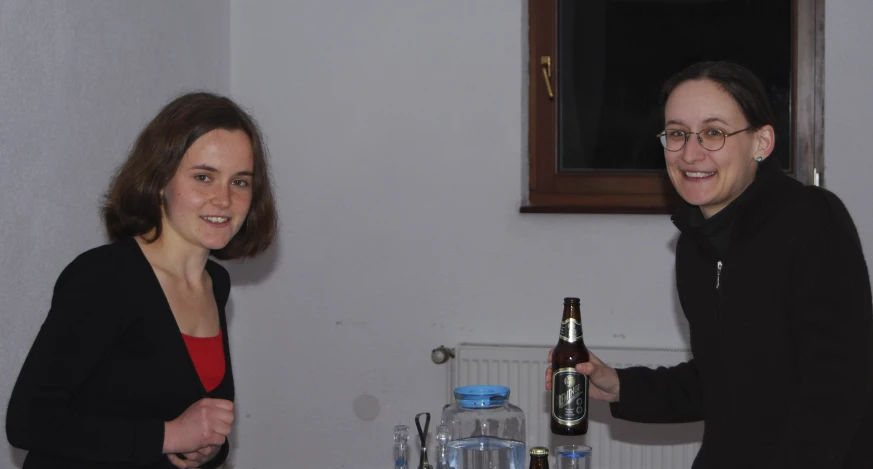 two woman standing at a table with beer bottles