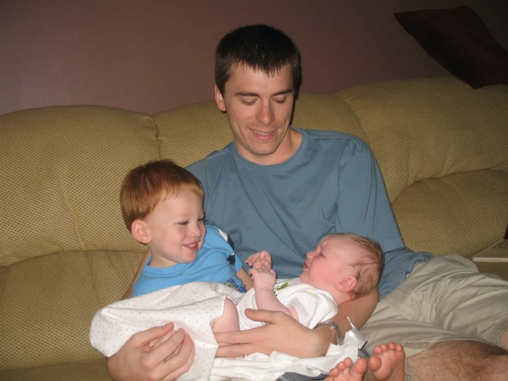 the man is holding three little s on the couch