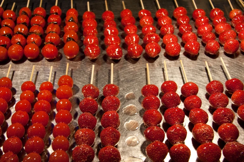 skewers full of strawberries on a silver grill