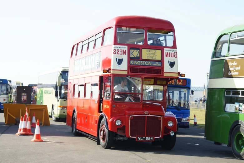 double decker buses are parked near construction cones