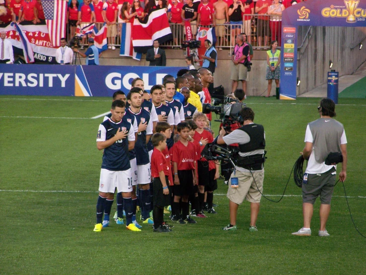 several children with a camera posing for the camera on a soccer field