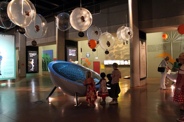 a group of s looking at artwork displayed on glass balls