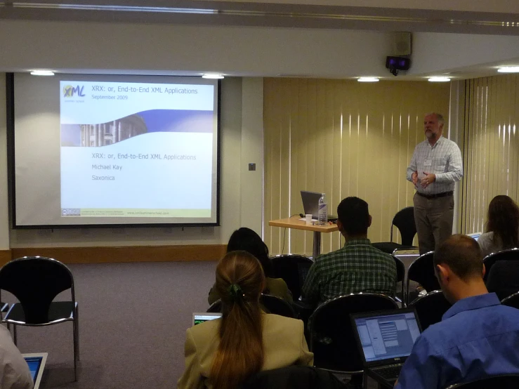 man speaking to students in front of a large screen