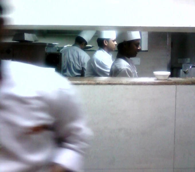 there are several chefs standing in a kitchen preparing food