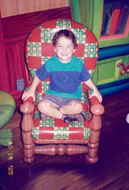 a child sitting on a red chair smiling