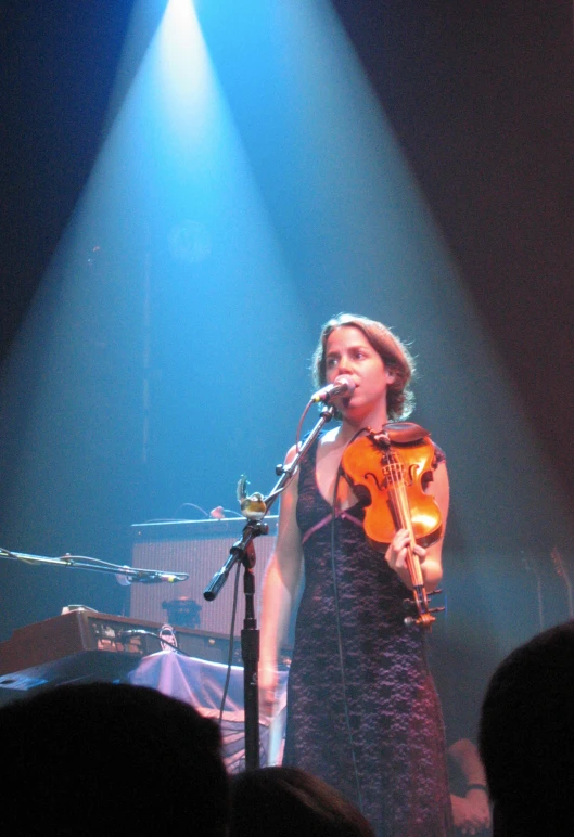 woman with violin on stage in front of microphones