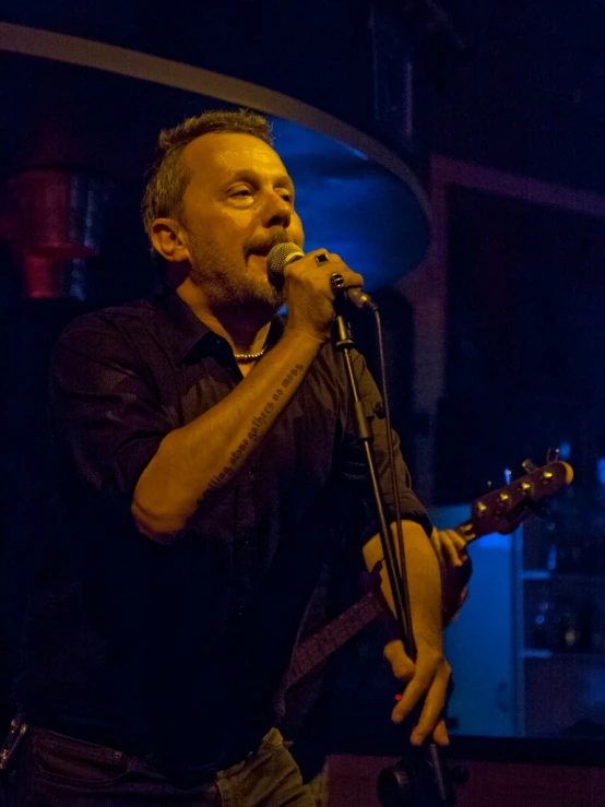 a man on stage singing into microphone with a guitar