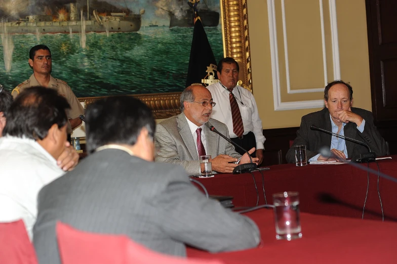 people sitting down at a meeting with microphones in front of them