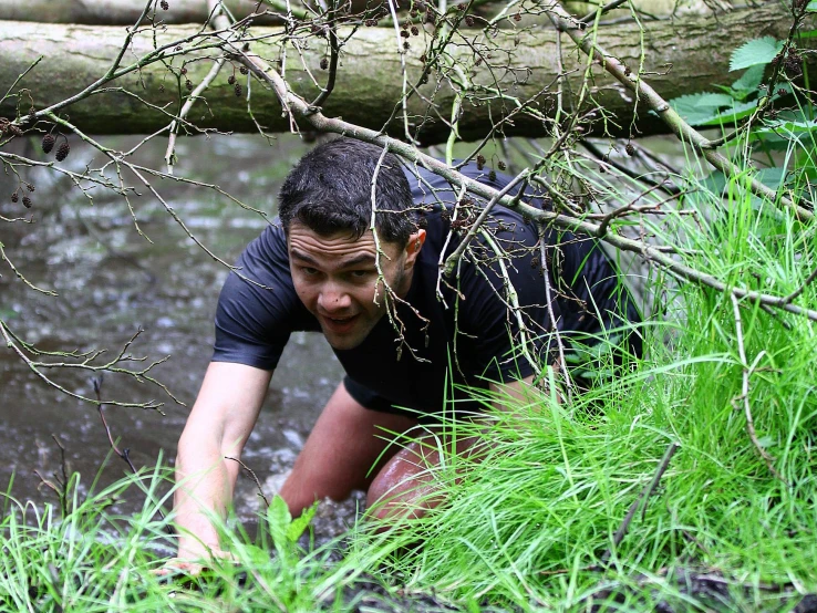 a man crouches in the grass while holding a nch