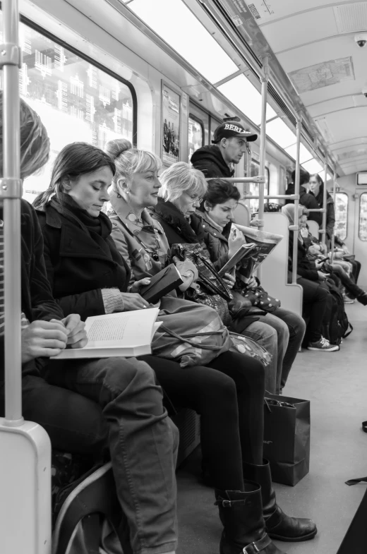 a group of people riding a train and reading on the seats