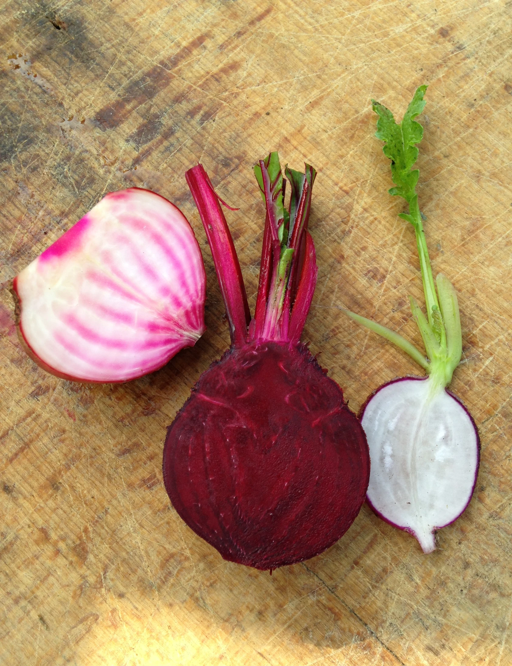 a purple colored carrot and onion are on a wooden surface