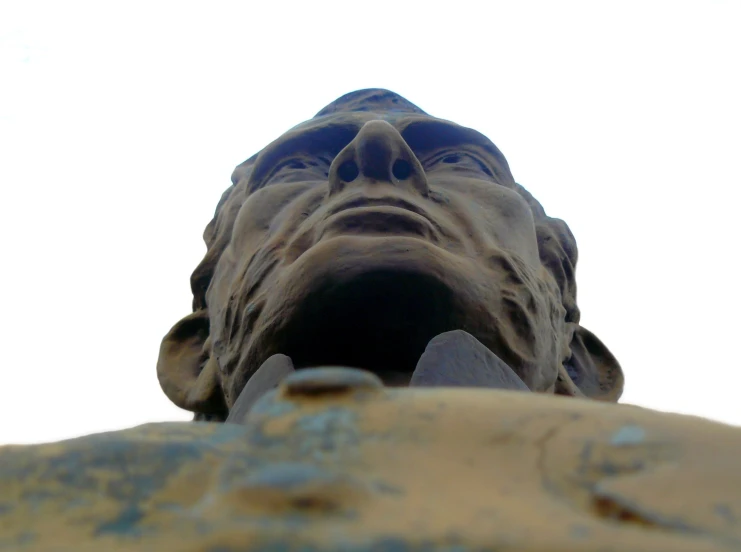 an old statue is sitting in front of the sky