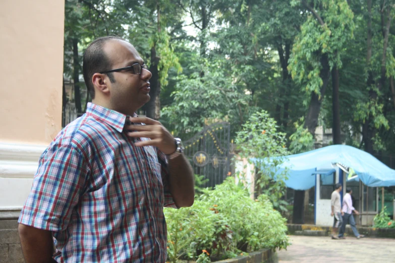 man in plaid shirt talking to another person outside