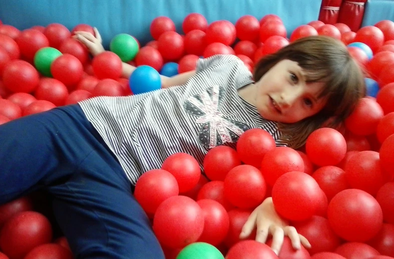 there is a girl playing in the ball pit