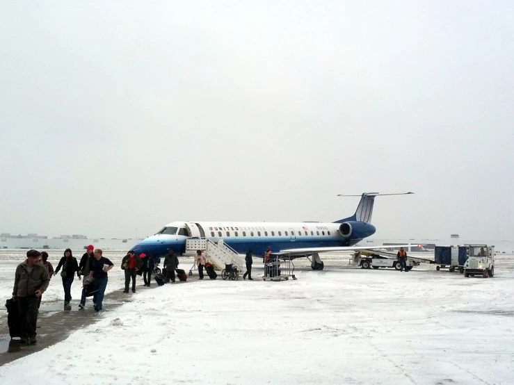 group of people getting off a small plane on a snowy airport