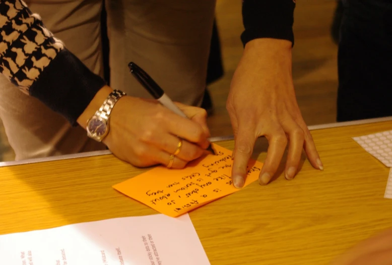 a person is signing a note at a table