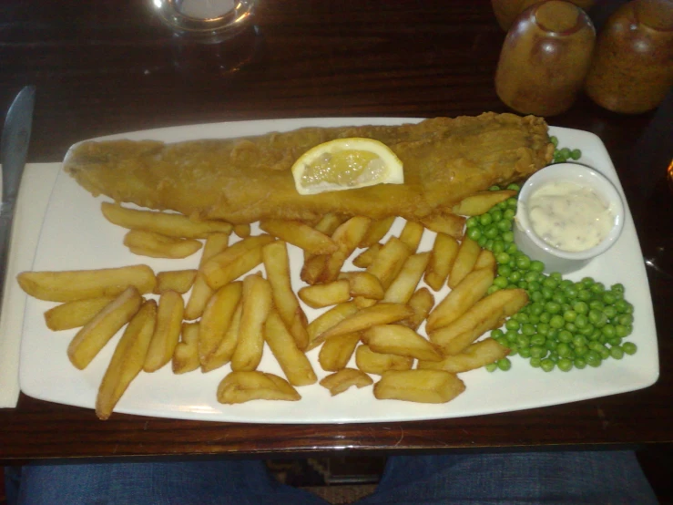 fish and fries served on a square plate with green peas