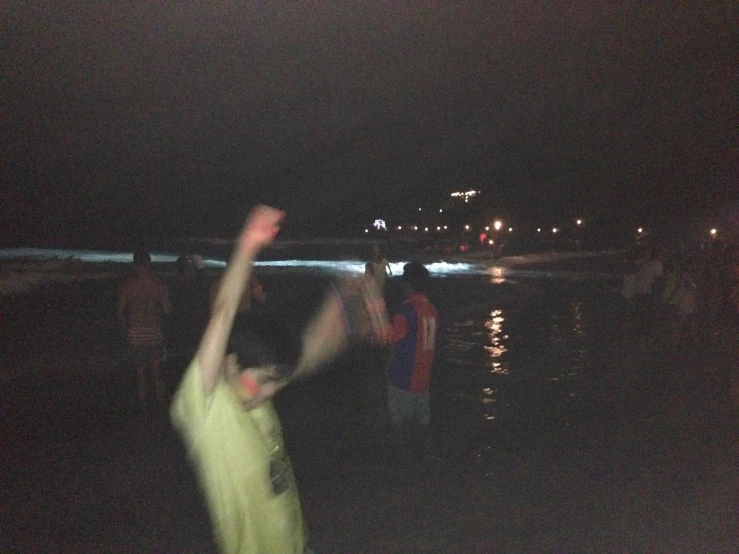 a man is flying an orange kite in a dark ocean