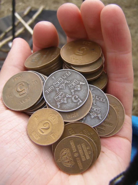 a person holding a handful of different euro coins