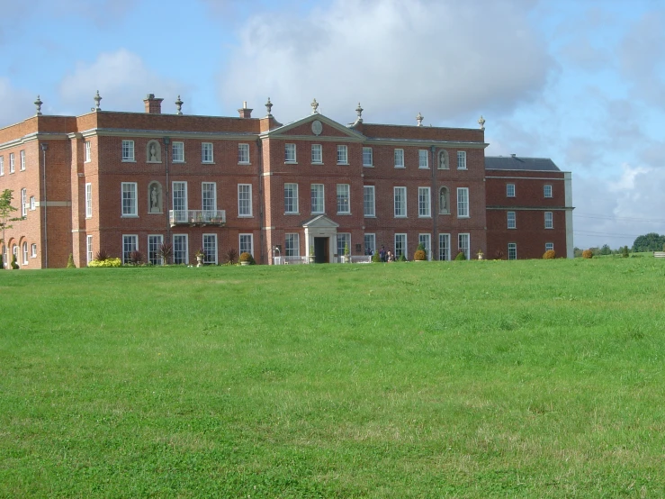 a large red brick building surrounded by lush green grass