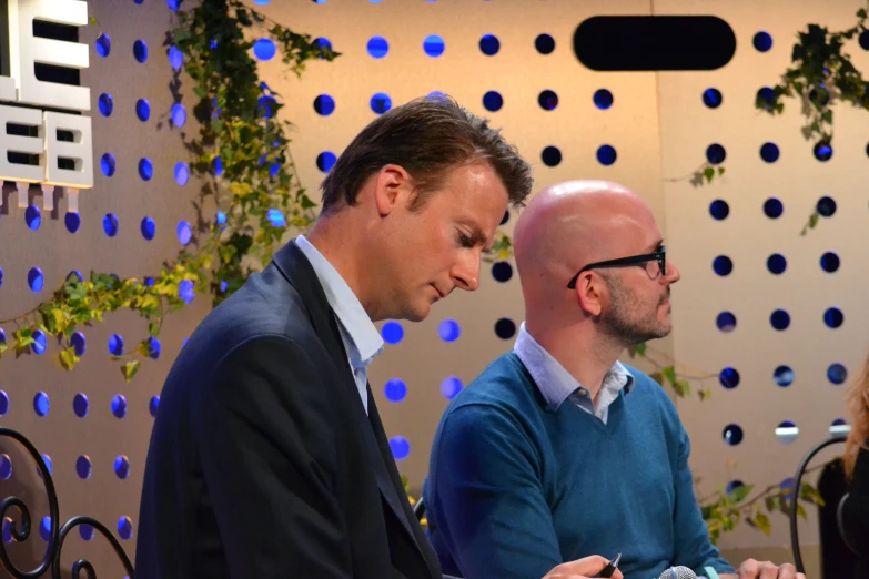 two men sitting at a table and looking down