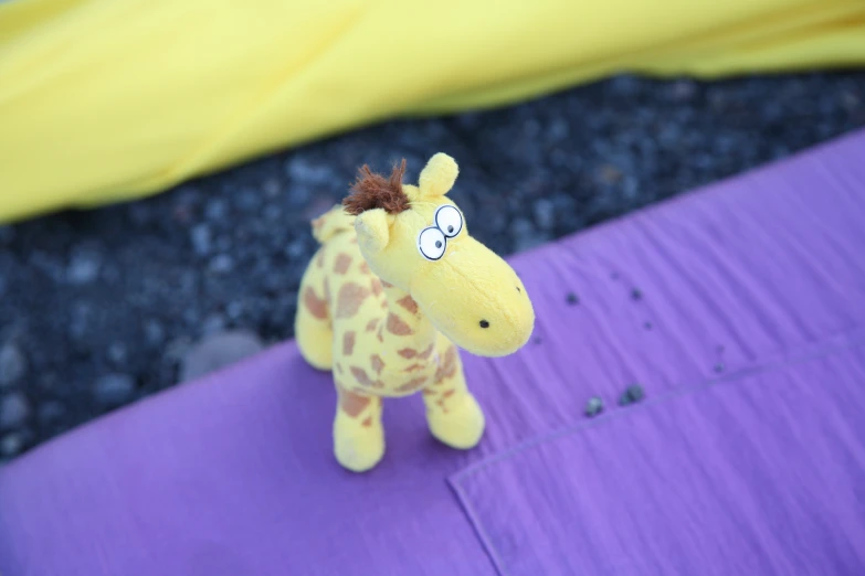 an odd toy giraffe that is on some purple cloth