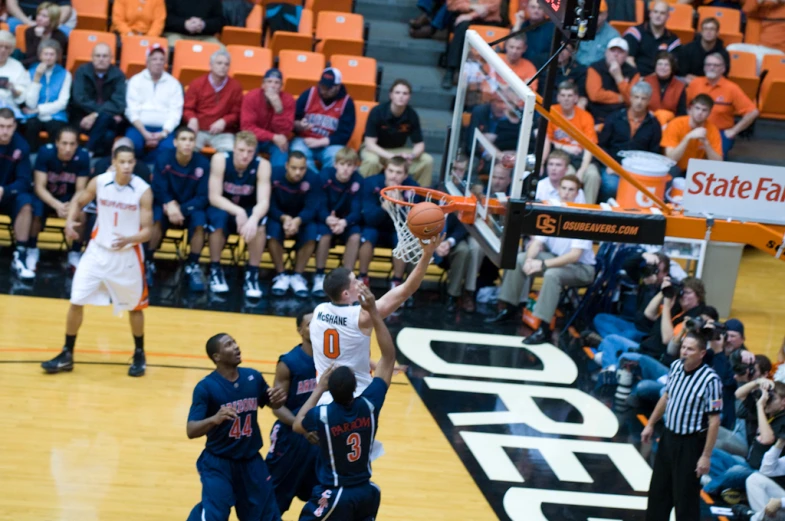 a player goes to dunk the basketball as others look on