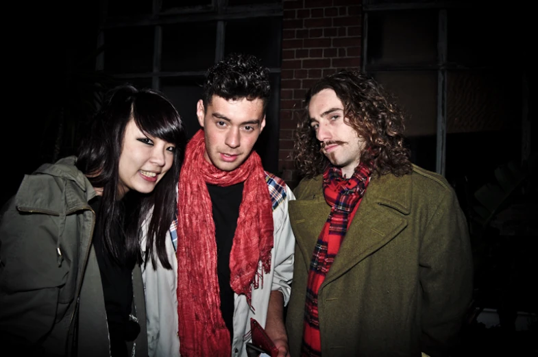 three people standing together in front of a building