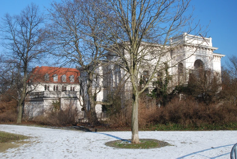 a stone building surrounded by tall trees and a snow covered ground