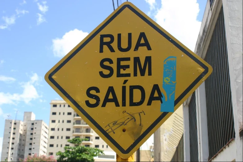 a yellow and black sign on a pole on the side of a building