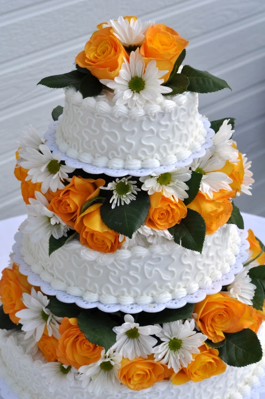 a large multi layer cake with orange roses and leaves on it