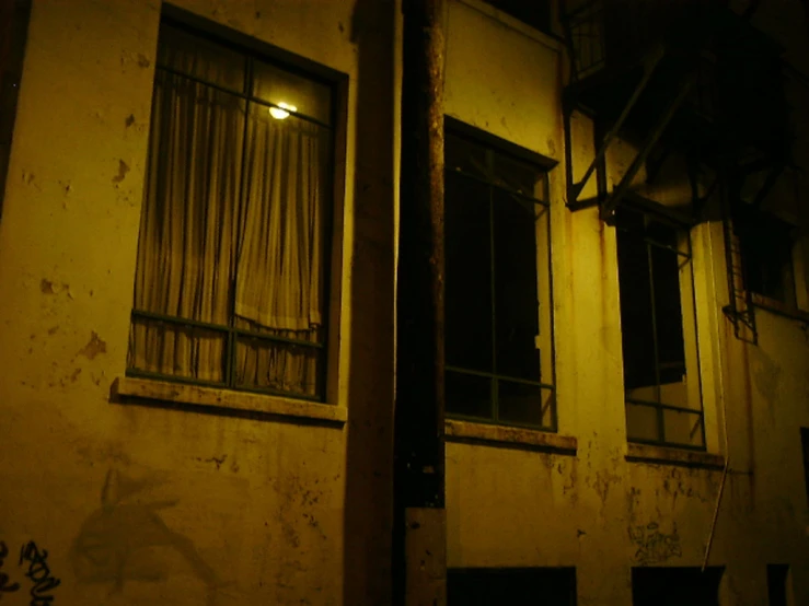 a dark street corner with graffiti on the wall and windows