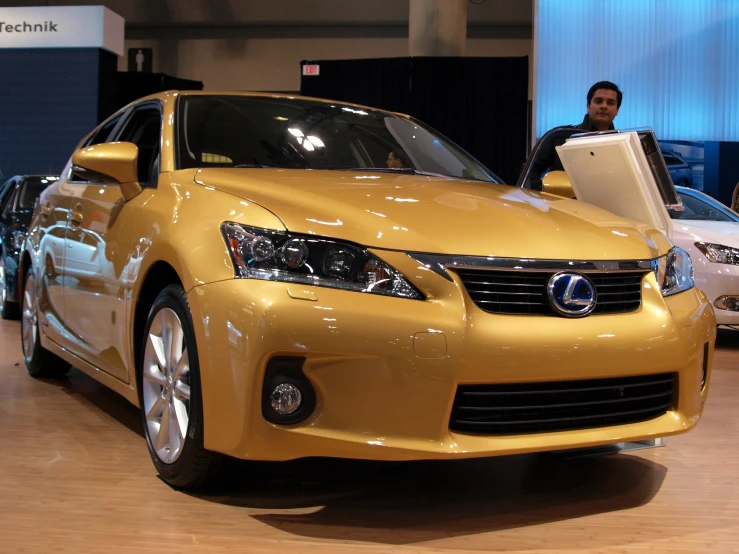 a man using a laptop while seated behind a sleek car