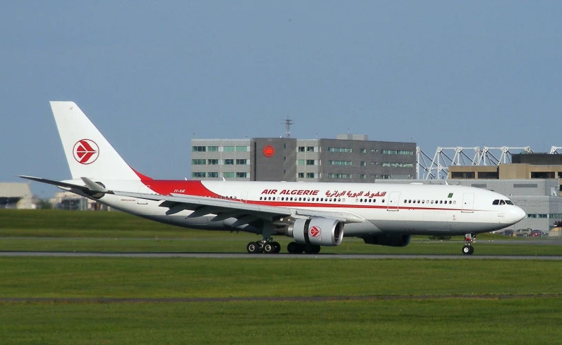 a plane on a run way with grass and buildings in the background