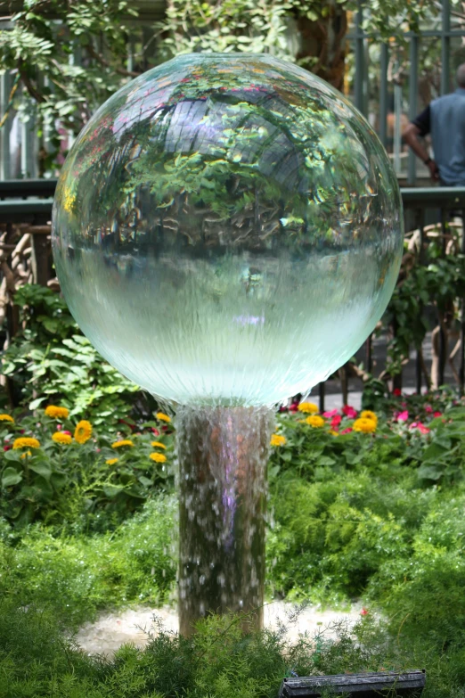 a glass sphere sculpture in a field of grass