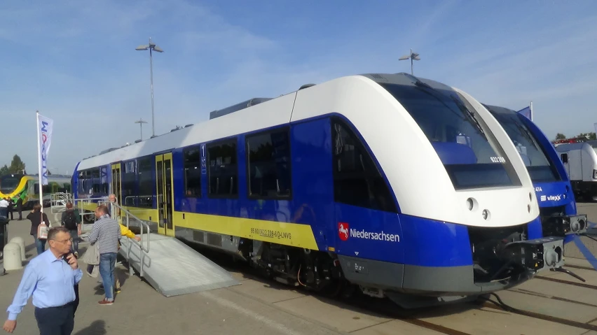 a train with blue, yellow, and white paint parked at a platform