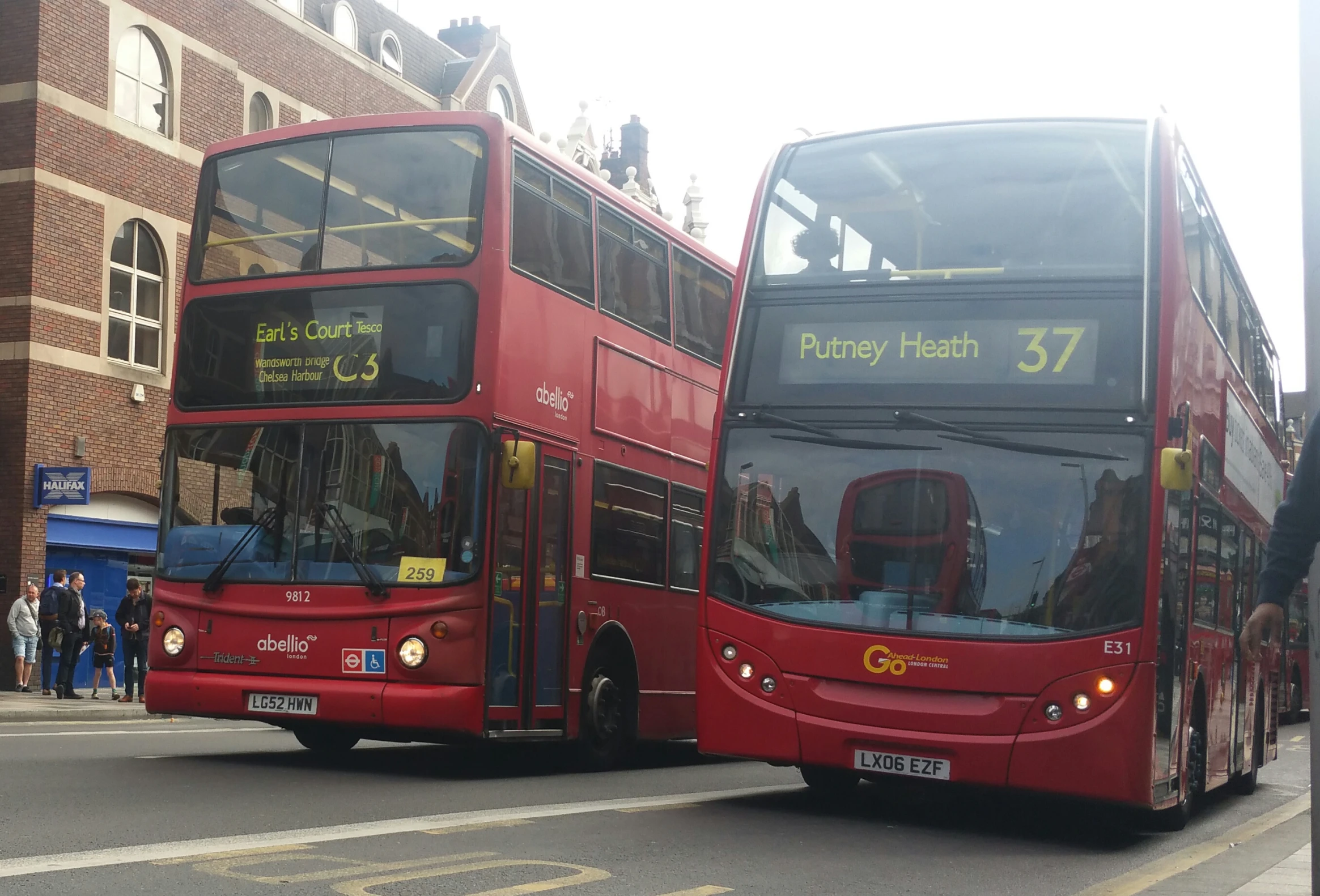two double decker busses on street in front of brick buildings