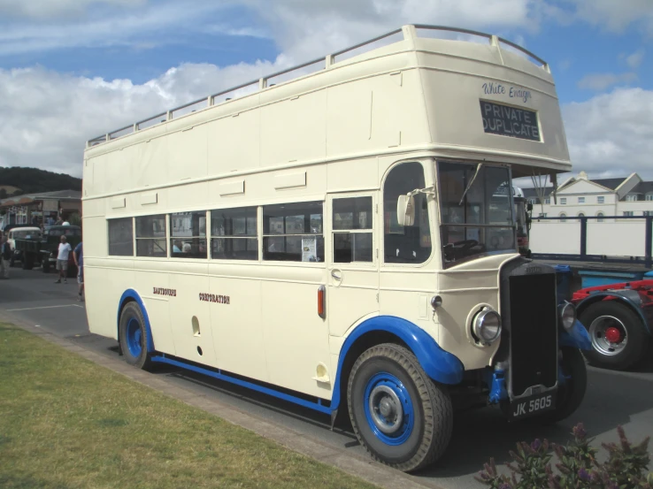 an old cream and blue double decker bus parked next to a tractor