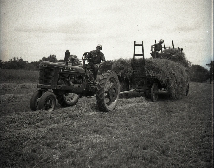 a farmer in a tractor pulls his bale of hay