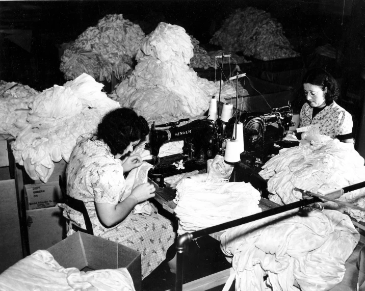 an old picture of two women using a sewing machine