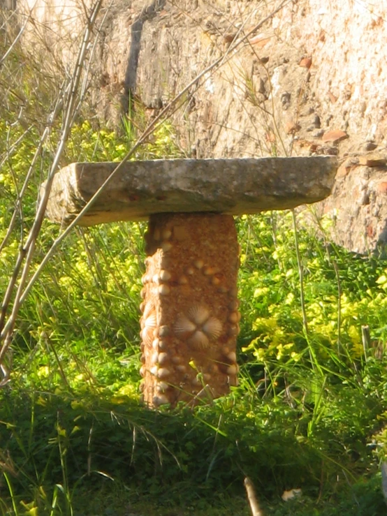 an old stone object surrounded by plants