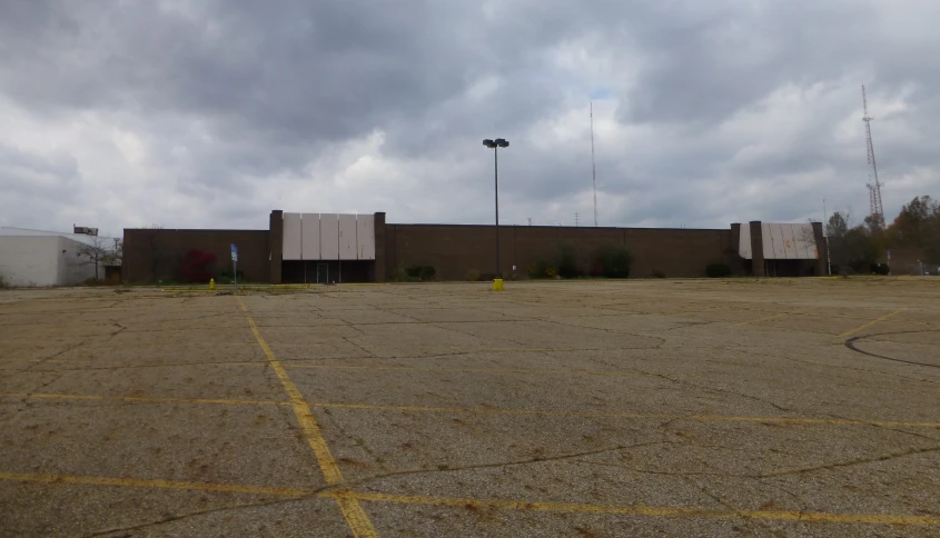 empty parking lot next to building under cloudy sky