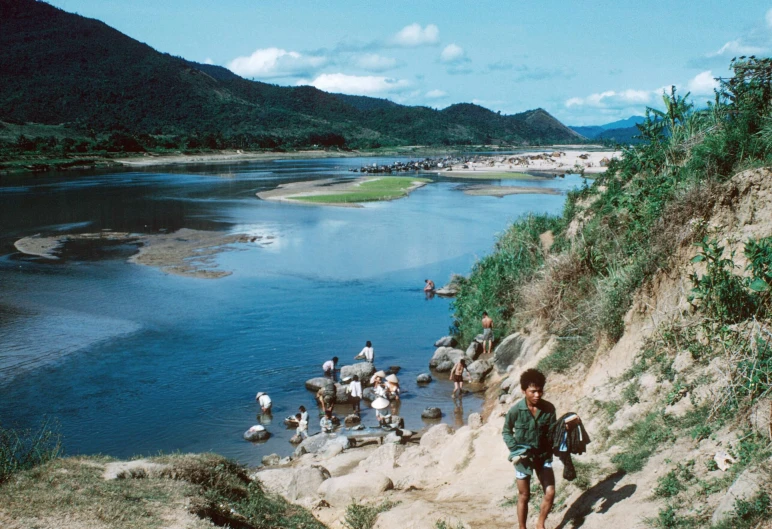 people on donkeys walk along a hill above water