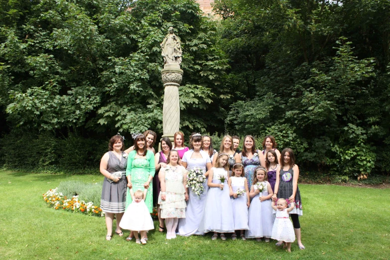 bridesmaids pose with their daughter in front of a statue