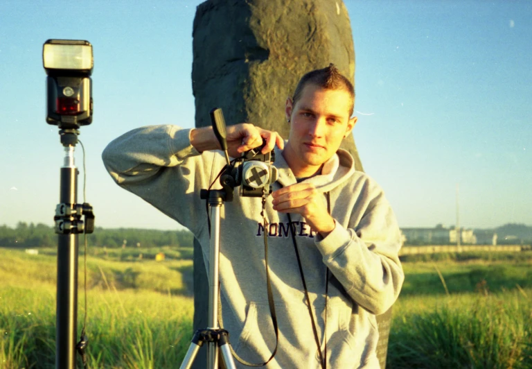 a man standing by a rock is taking a picture with a camera