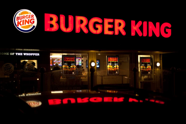 the exterior of a burger king restaurant lit up in the dark